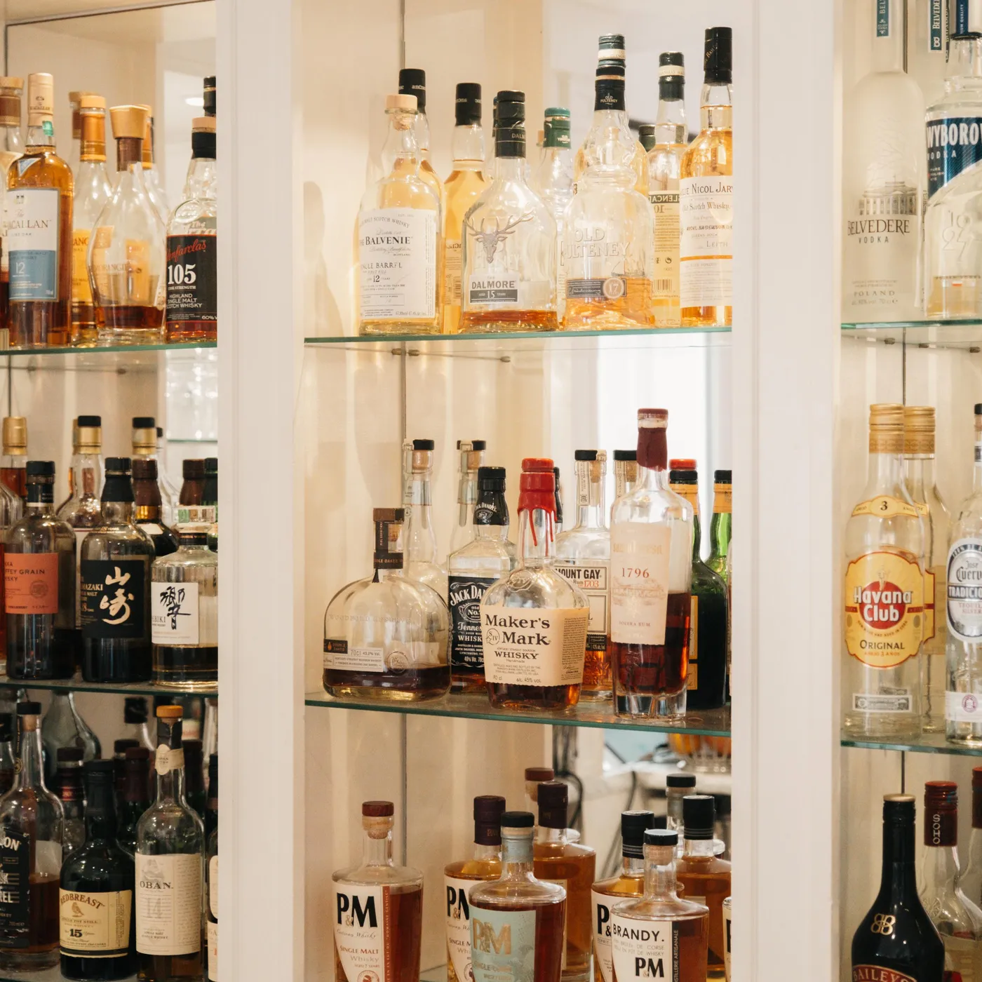 A shelf filled with bottles of alcohol from various brands and colors