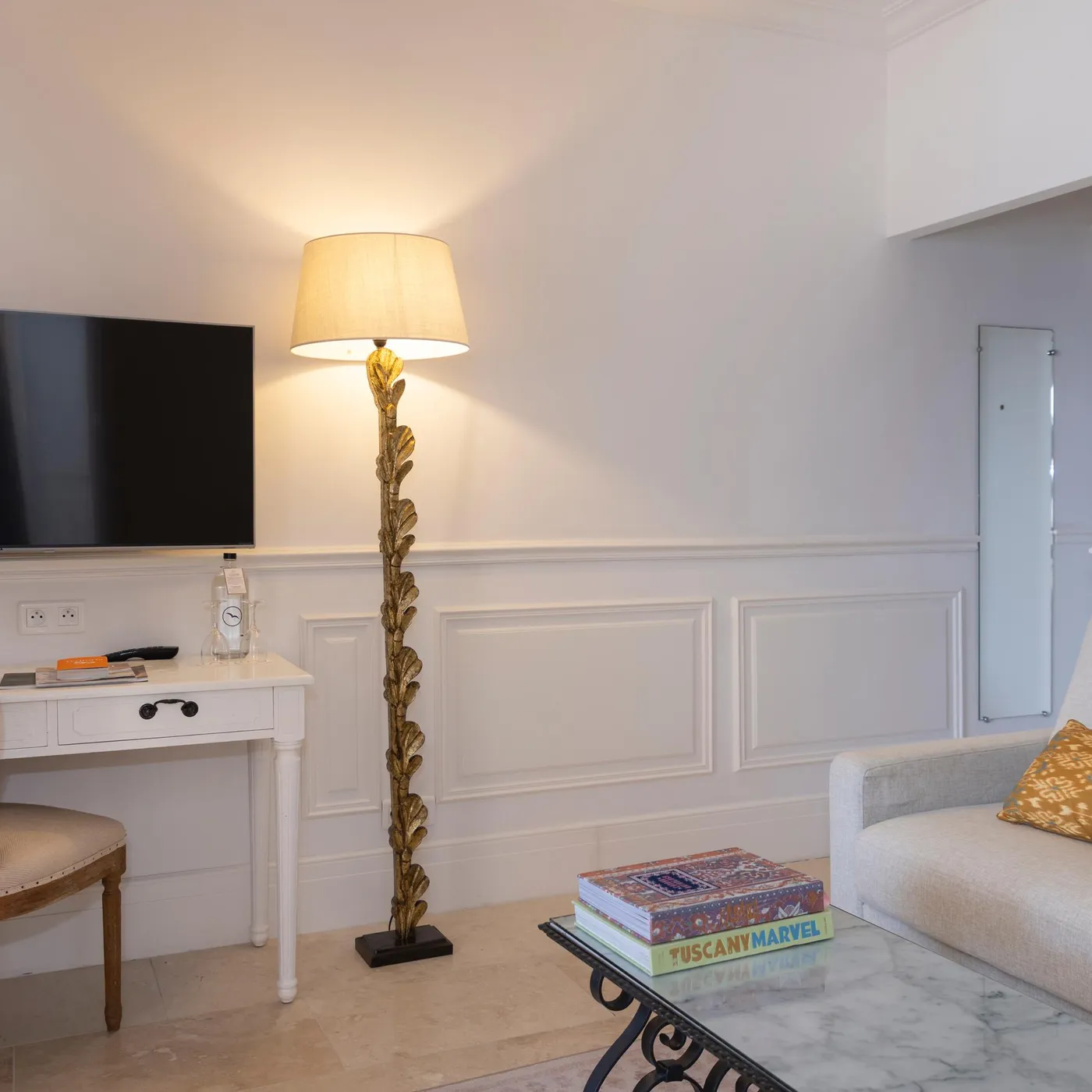 Living room with sofa, coffee table, decorative lamp, television, and white desk