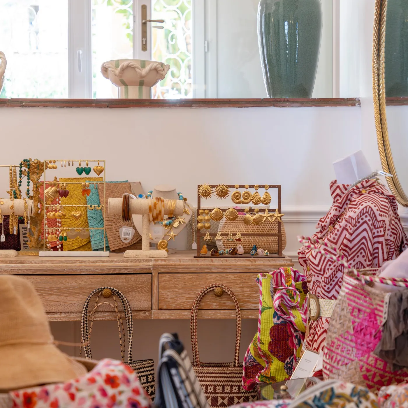 A shelf displays jewelry, bags, and decorative accessories in front of a window and a mirror.