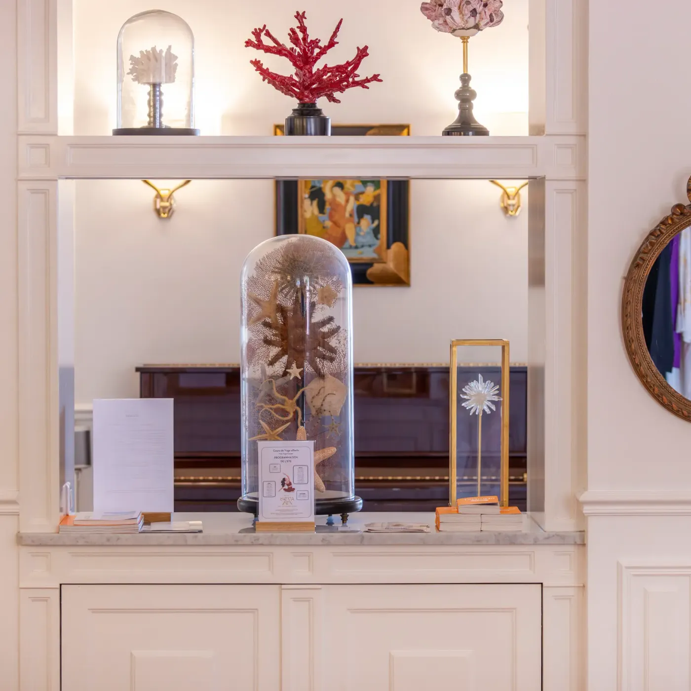 A shelf with objects under glass domes, mirrors, and documents, in a decorated room