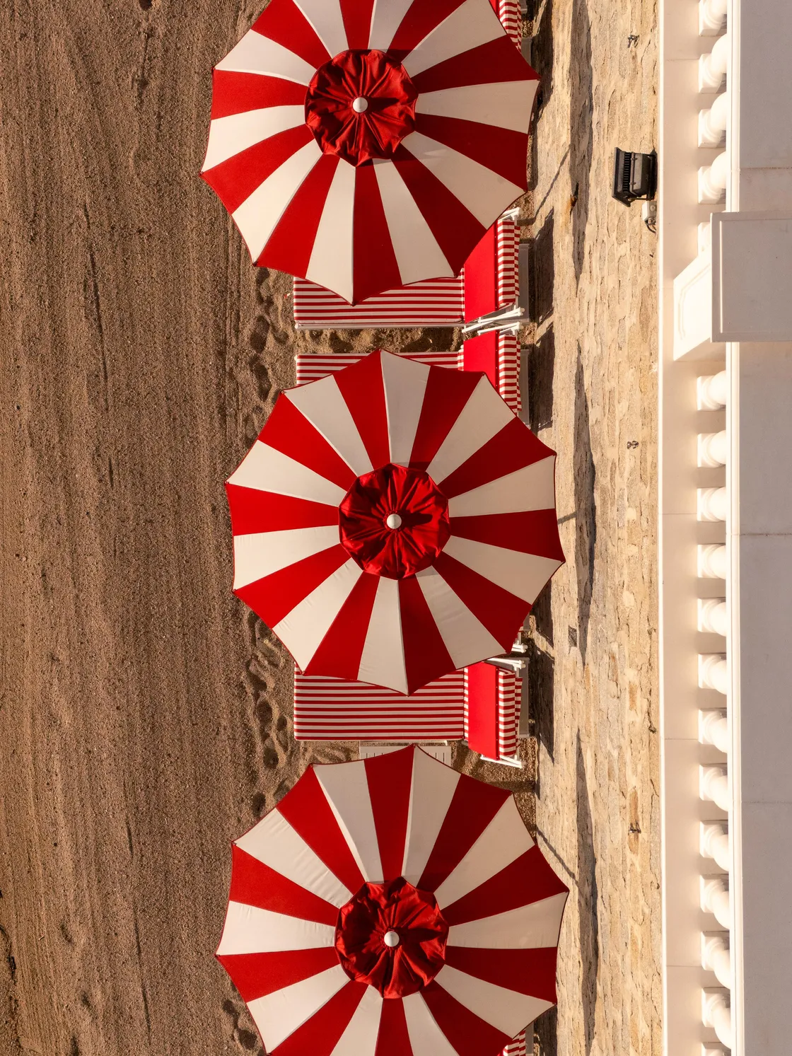 Vier rode en witte gestreepte parasols op een zandstrand opgesteld