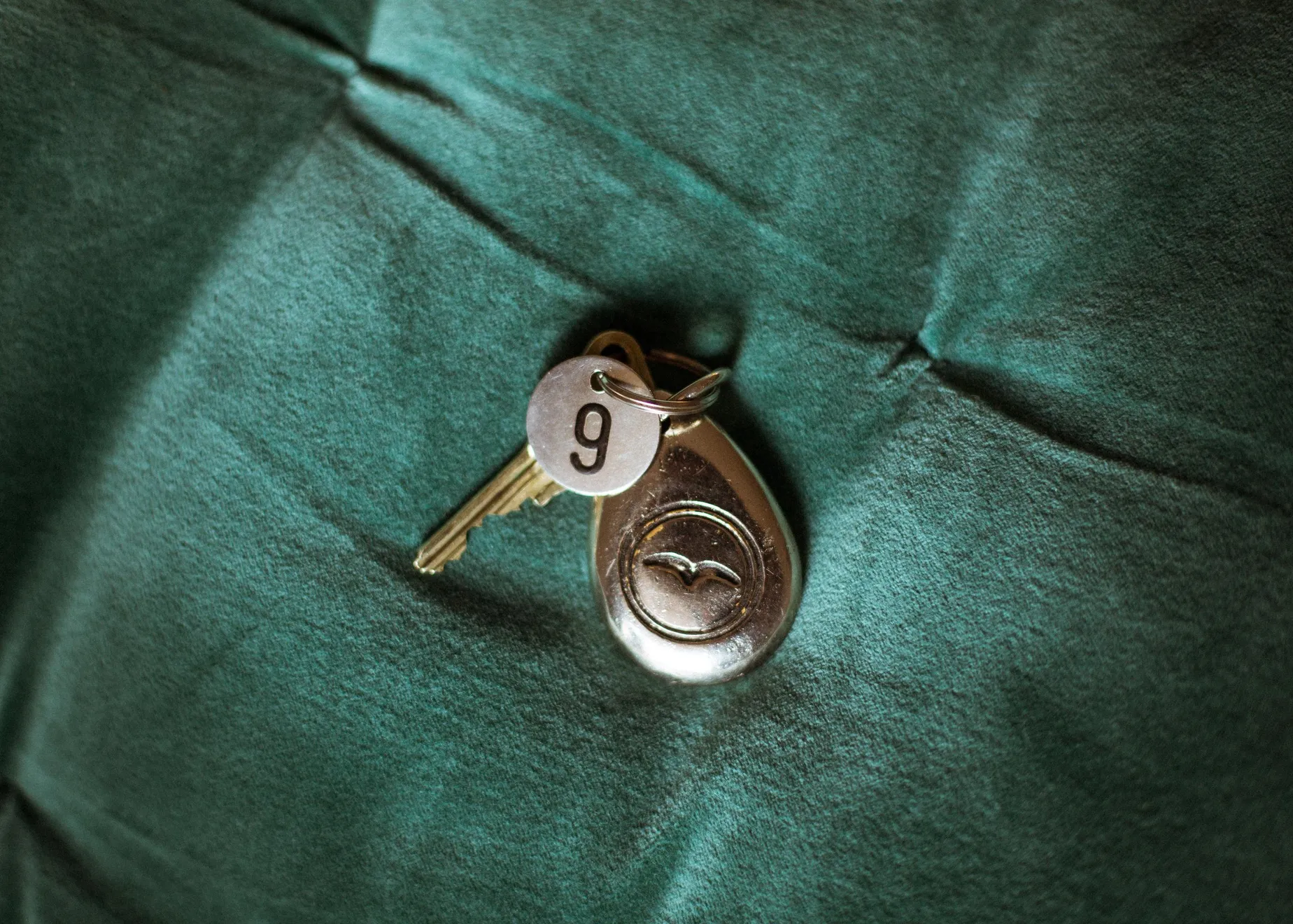 Een sleutel met een sleutelhanger met het cijfer 9 erop ligt op een donkergroen weefsel