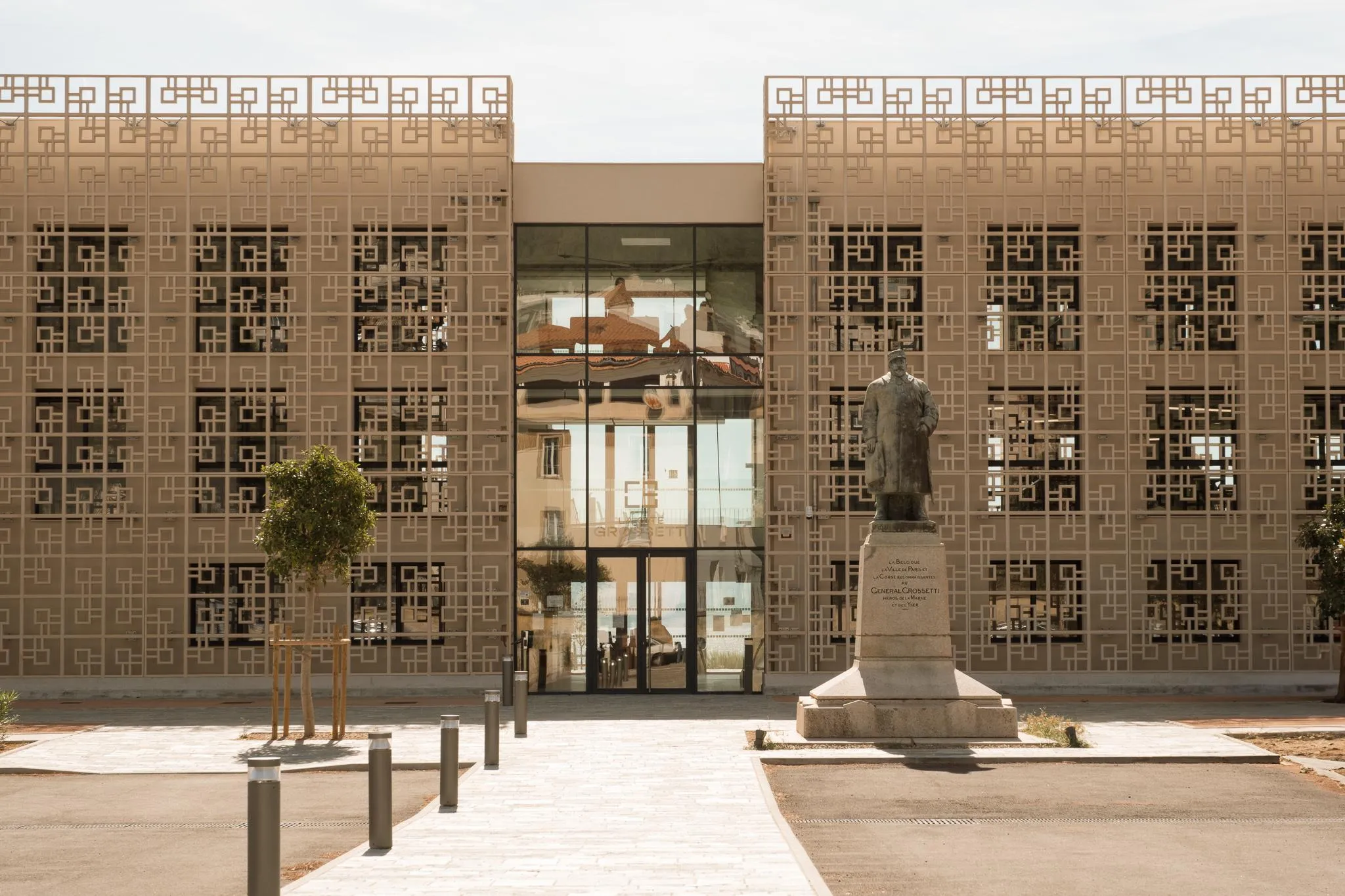 Modern building with geometric-patterned facade and statue of a man in a suit in front of the entrance
